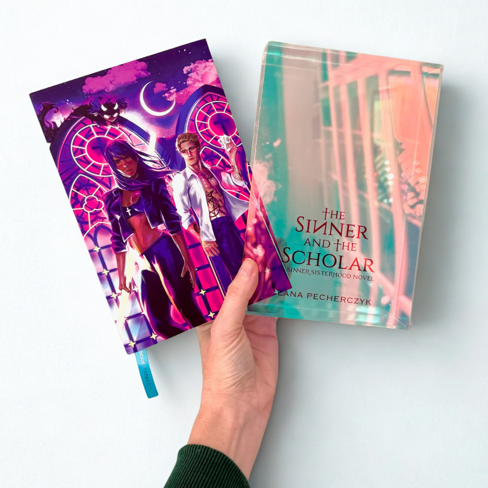 Two books titled 'The Sinner' and 'The Scholar' held by a hand on a light background. for fans of buffy, supernatural tv, and constantine but with spicy romance